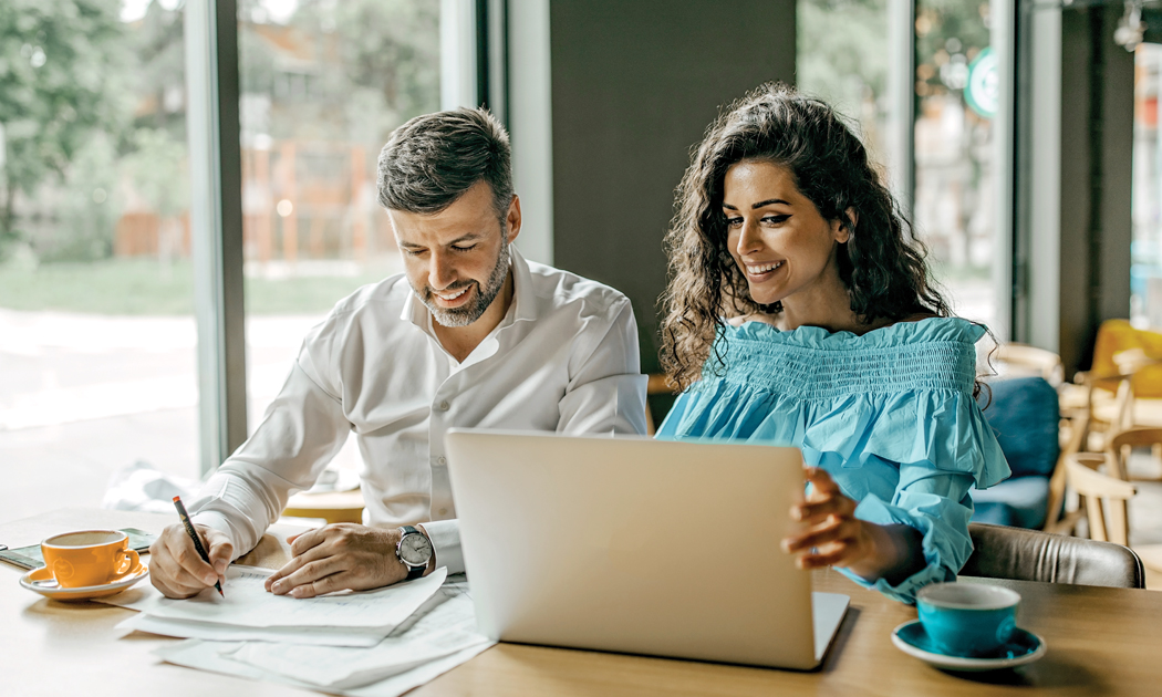couple looking over laptop and taking notes together
