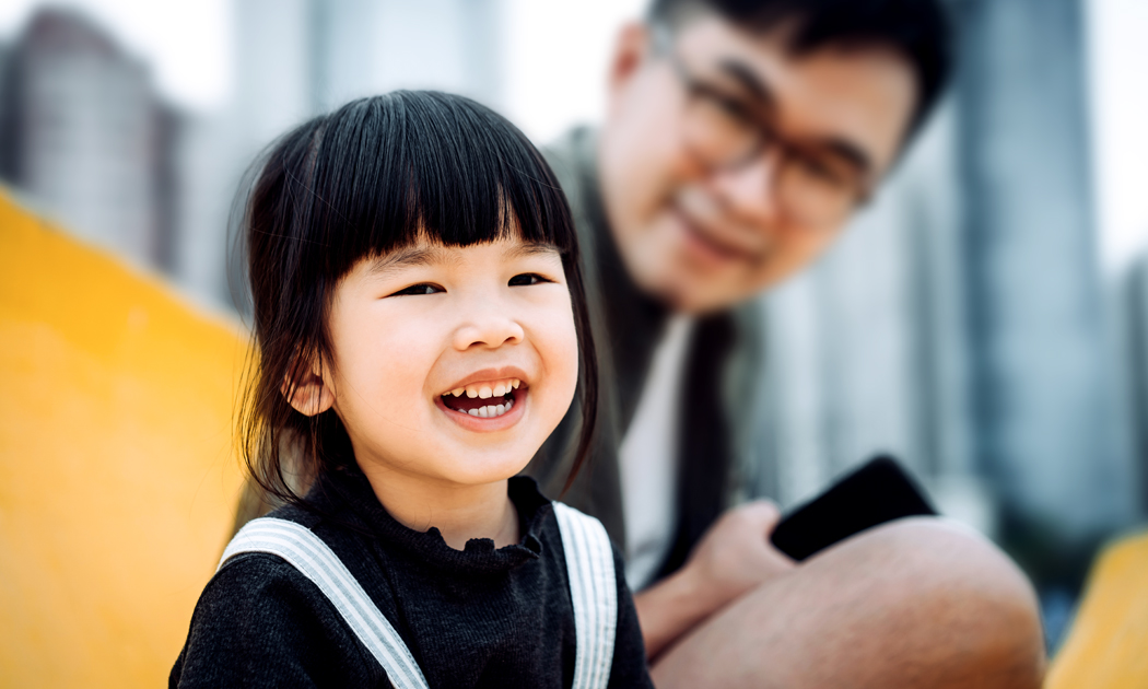 little girl toddler smiling with her father in the background